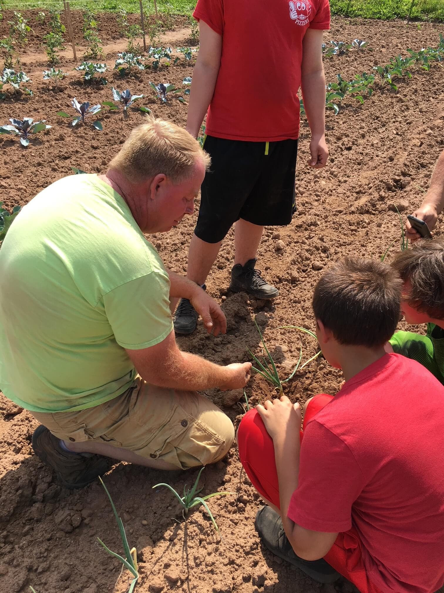 Adult teaching kids to plant in soil