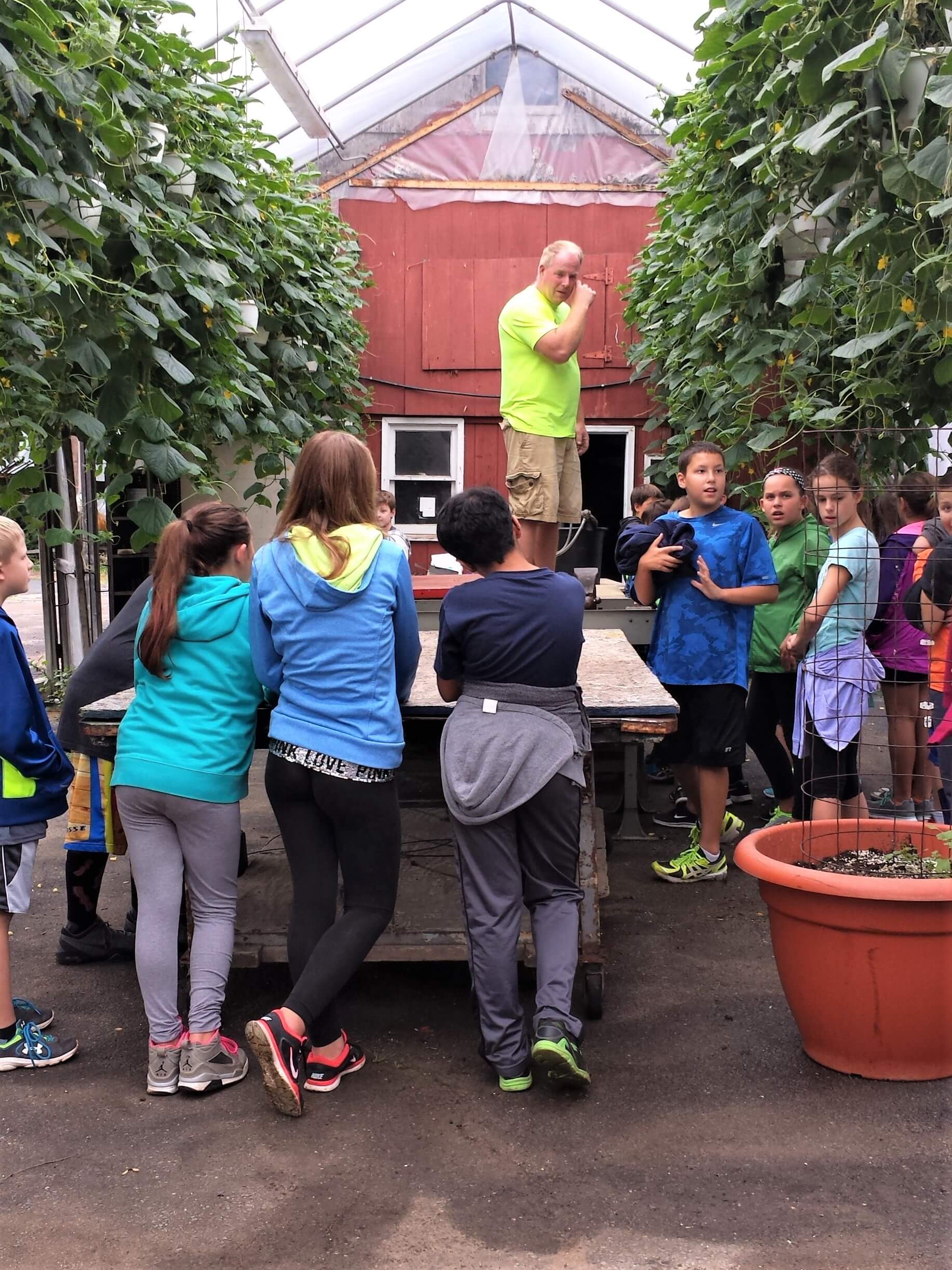 Kids in greenhouse learning from instructor
