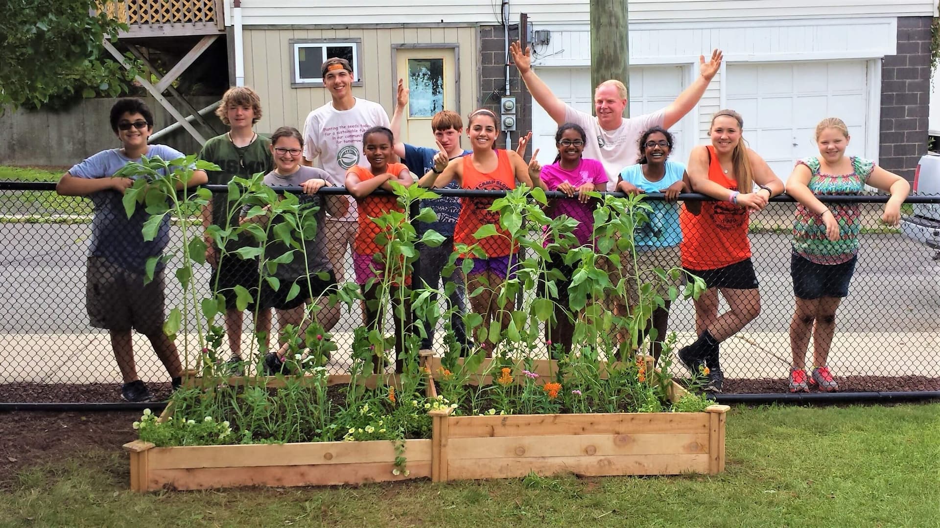 Group photo of students behind raised garden bed with sunflowers